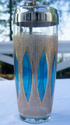 a blue and gold glass vase sitting on top of a white tablecloth covered table