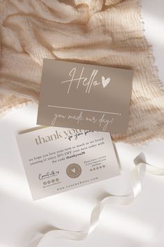 a white and silver wedding card with a heart on it, sitting next to a blanket