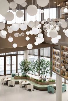 a large room filled with lots of white balls hanging from the ceiling and tables in front of windows