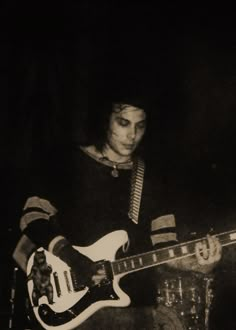 a man playing an electric guitar in the dark