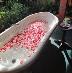 a bathtub filled with red and white confetti next to a small table