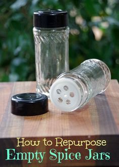 an empty spice jar sitting on top of a wooden table next to a glass bottle