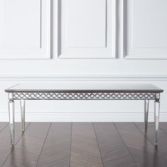 a glass table sitting on top of a hard wood floor next to white paneled walls