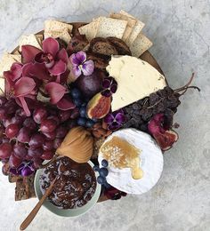 a platter filled with cheese, grapes and crackers