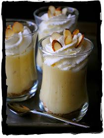 three desserts in small glass dishes with spoons on the side and one is topped with whipped cream