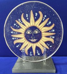 a blue plate with a sun painted on it's face and two small candles in front of it