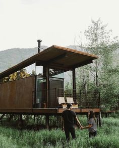 two people standing in front of a small house