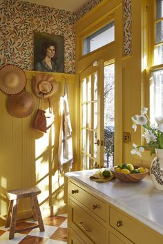 a kitchen with yellow walls and white counter tops, decorated with pictures on the wall