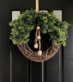 a wreath hanging on the front door with bells and greenery around it's edges