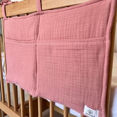 a baby crib with a pink blanket hanging from it's side