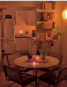 a small kitchen with a table and chairs in the center, next to a refrigerator