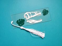 a paper cut out of a dinosaur with leaves and a tassel on the side