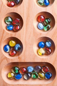 several wooden bowls filled with marbles on top of a wood table next to each other