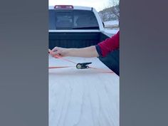 a person is pulling something out of the back of a truck in the snow on skis