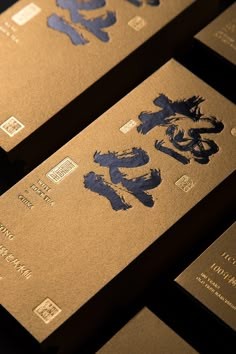 some gold business cards with blue ink on them and writing in chinese characters are displayed