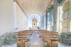 the inside of a church with wooden pews and flowers in vases on either side