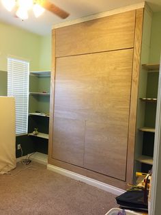 an empty room with some shelves in the corner and a ceiling fan on top of it