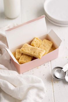 a box filled with short crackers next to two measuring spoons on top of a white table