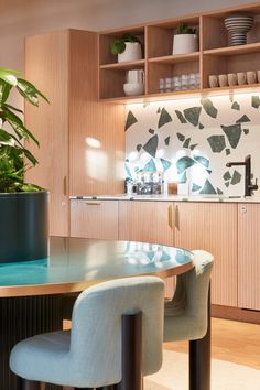 a dining room table and chairs with plants on the shelves behind them in a kitchen