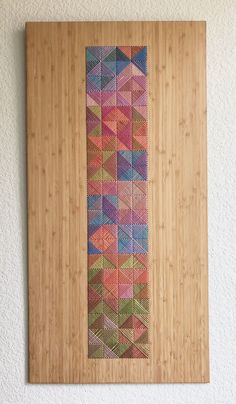 a wooden frame with a colorful design on it's side hanging on the wall