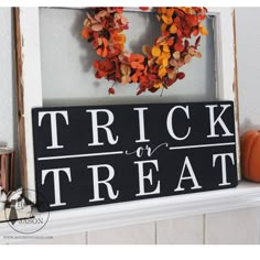 a sign that says trick or treat on the mantle next to a wreath and pumpkins