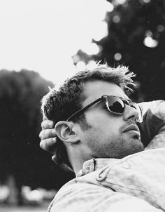 black and white photograph of a man with sunglasses resting on his arm, looking off into the distance