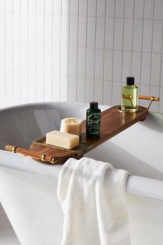 a bathtub with soap, shampoo and other items on the tray in front of it