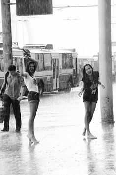 two girls are standing in the rain with umbrellas on their head and one girl is holding an umbrella