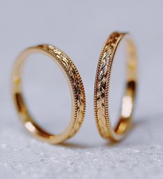 two gold wedding rings sitting on top of each other