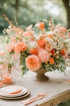 an arrangement of peach and white flowers in a vase on top of a wooden table