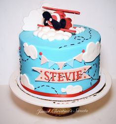 a blue cake decorated with a plane and name on it, sitting on a white plate