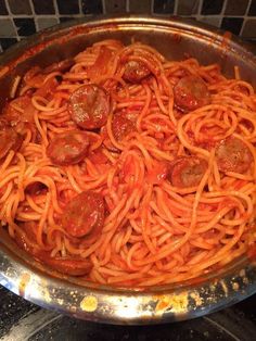 a pan filled with spaghetti and pepperoni on top of a stove