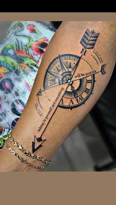 a woman's arm with an arrow and compass tattoo on it