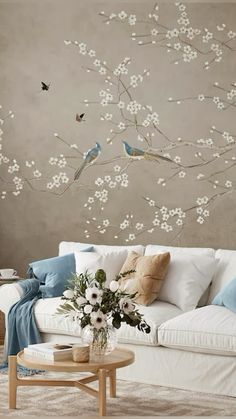 a living room with white furniture and flowers on the wall, birds flying in the air