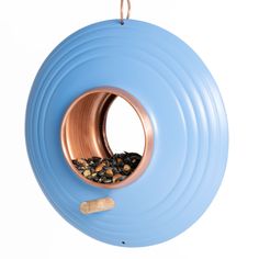 a blue bird feeder hanging from the side of a wall