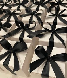 several white boxes with black bows on them are lined up and ready to be opened