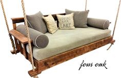 a wooden swing bed with pillows on it and a pillow hanging from the front end