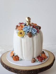 a white pumpkin decorated with flowers on top of a wooden slice