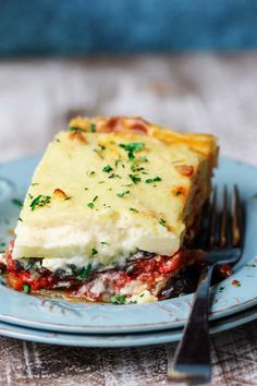 a piece of lasagna on a blue plate with a fork and knife next to it