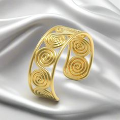 This stunning cuff bracelet is fit for the gods! Here, a timeless "figure-eight" spiral repeats across the wrist, within a strong, clean border. The design is based on a series of gold ornaments found within a 16th century BC burial in Grave Circle A, at Mycenae. The grave, which belonged to a woman, was filled with gold jewelry and accoutrements. In ancient Greek mythology, Eupraxia was the personification of well-being. Her name was derived from the ancient Greek word for "good conduct" (Εὐπρα Ancient Bracelet, Ancient Greek Jewelry, Ancient Greek Mythology, Ancient Greek Words, Roman Jewelry, Gold Vermeil Jewelry, Jewelry Catalog, Greek Jewelry, Gold Ornaments