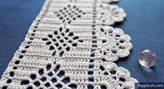 a crocheted table runner next to a crystal beaded object on a blue surface