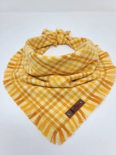 a yellow and white checkered scarf with a brown leather tag hanging from the neck