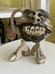 a ceramic sculpture of a monster with its mouth open and teeth wide open, sitting on a table