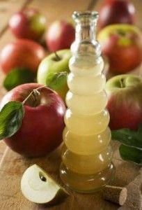 an apple cider sitting on top of a wooden table next to apples and leaves