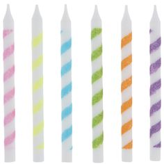 five different colored candles are lined up in a row on a white background, one is brightly lit and the other has multicolored stripes