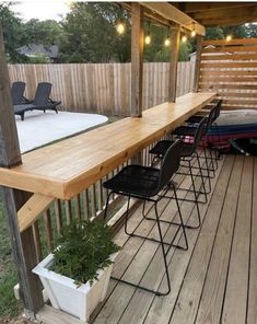 a wooden deck with chairs and plants on it, next to a fenced in area