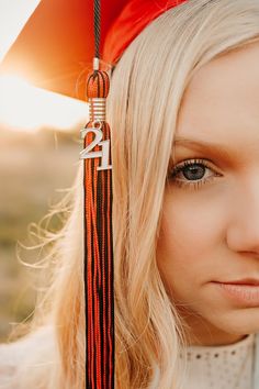 a woman with long blonde hair wearing a graduation cap and tassel, looking at the camera