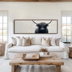 a living room filled with furniture and a cow painting on the wall above it's head