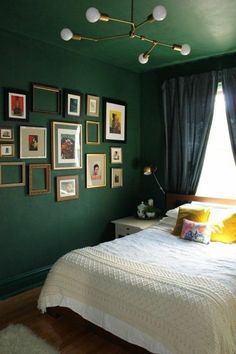 a bedroom with green walls and pictures hanging on the wall, along with a bed