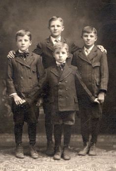 an old black and white photo of four boys